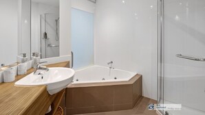 Ein modernes Badezimmer mit einer großen Badewanne, einem Waschbecken und einer Duschkabine aus Glas.