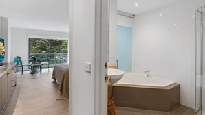 Ein modernes Badezimmer mit einer großen Badewanne, einer Duschkabine aus Glas und Blick ins Freie.