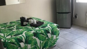 A room with a bed, a refrigerator, a television, and a painting on the wall.