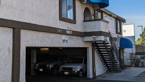 A building with a garage entrance, a staircase, and a blue awning.