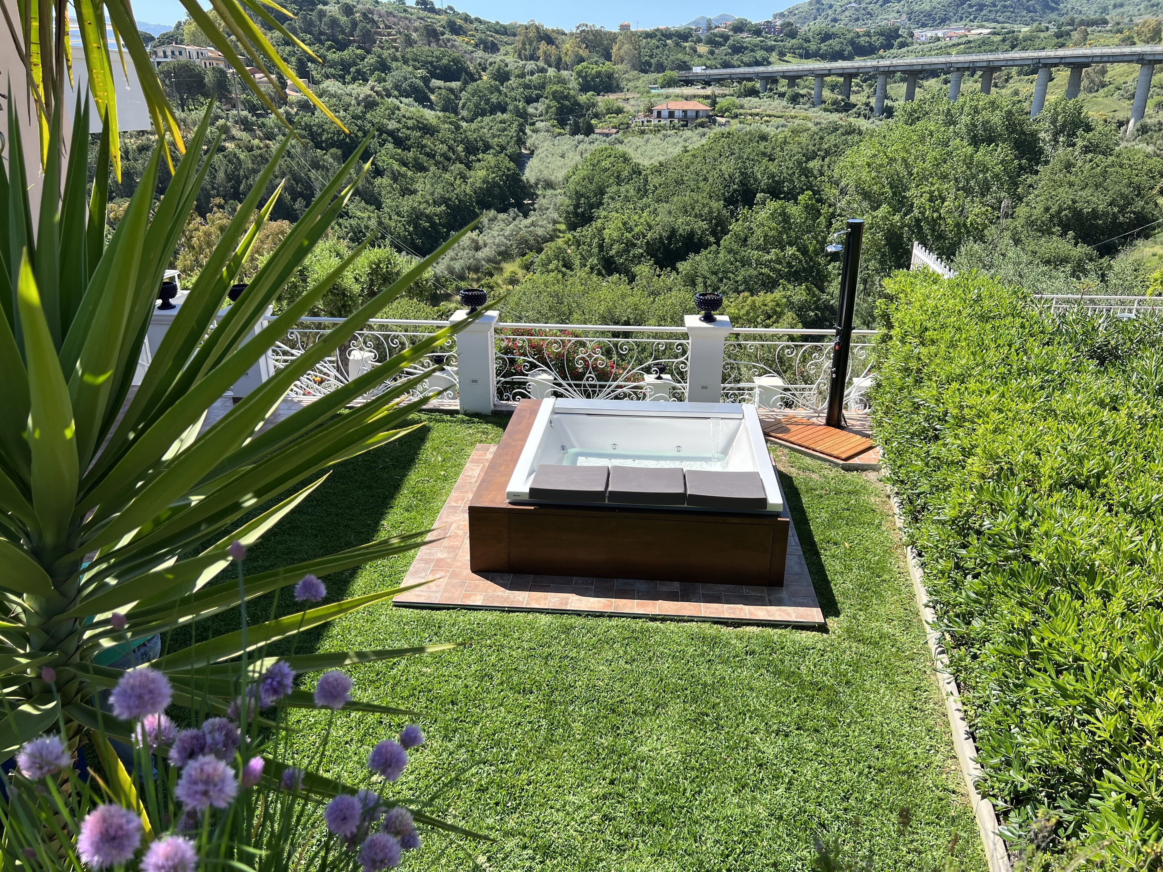 A hot tub on a well-manicured lawn with a view of a bridge and hills in the background.