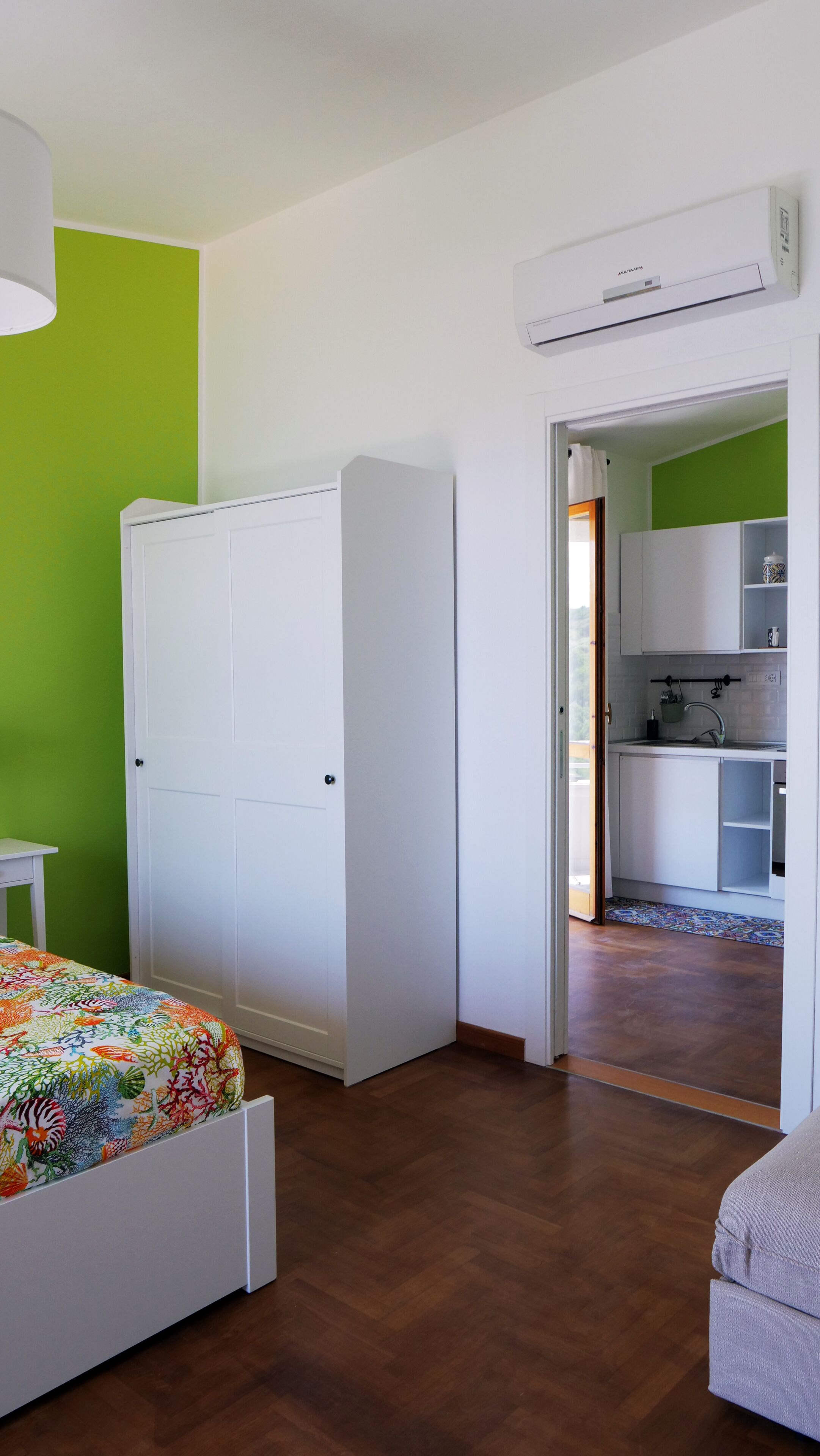 Un dormitorio con una cama, un armario y una kitchenette en la habitación contigua.