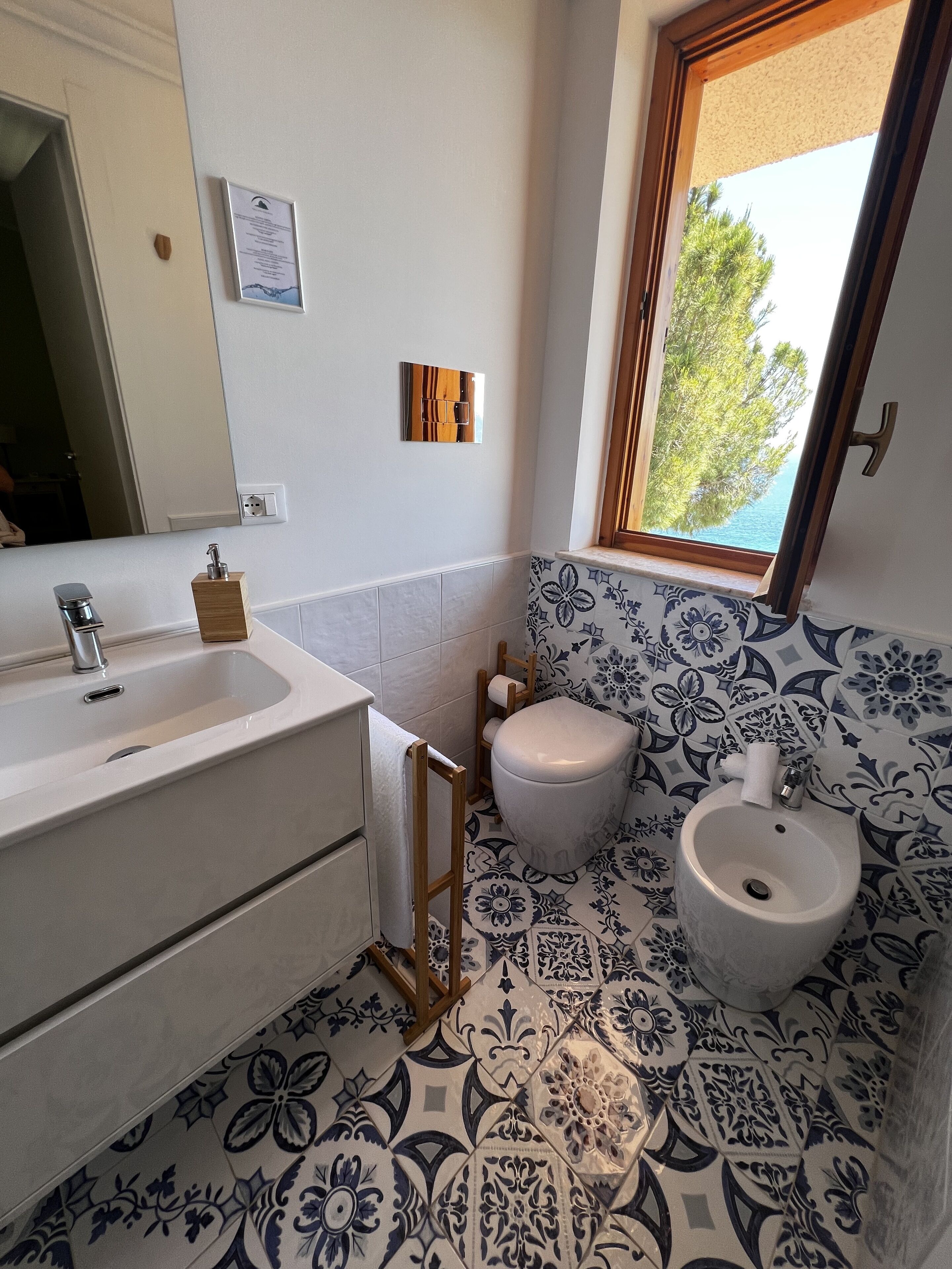 A bathroom with a sink, toilet, bidet, and patterned floor tiles.