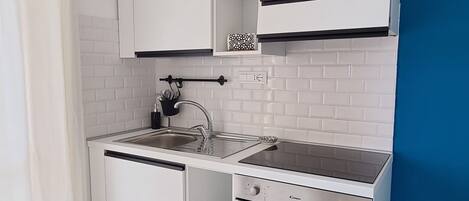 A compact kitchen with white cabinets, a built-in oven, and a sink.