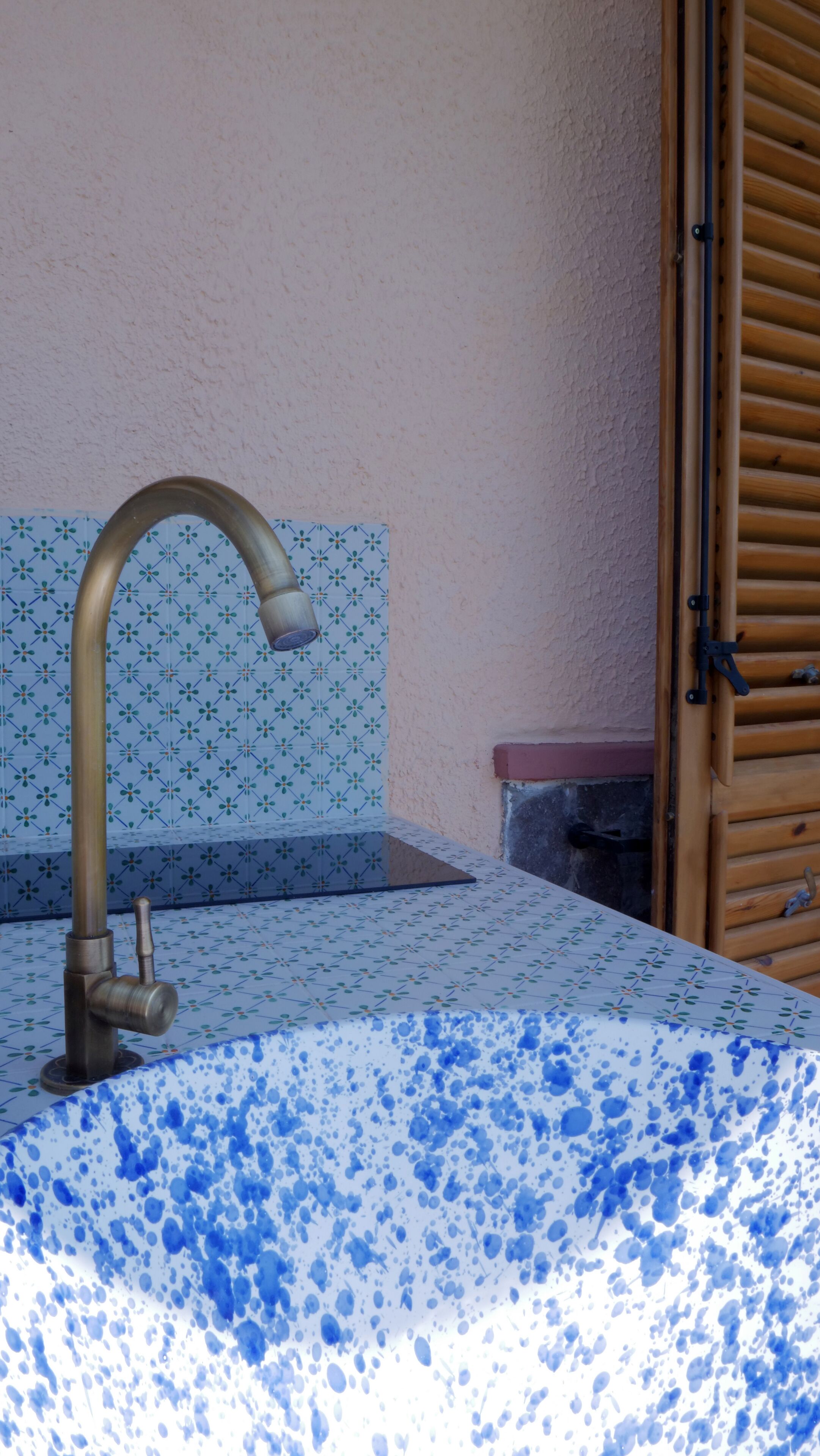 A bathroom with a sink, a faucet, and a shower area.