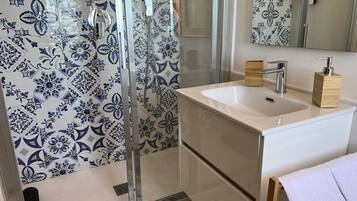 A bathroom with a shower, a sink, and a mirror.