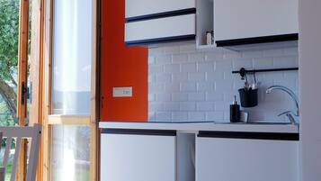 A modern kitchen with white cabinets, a black countertop, and a red accent wall.