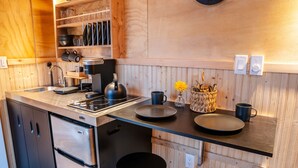 Eine moderne Küche mit eingebautem Herd, Kaffeemaschine und Spüle. Holzschränke und eine Holzarbeitsplatte sind ebenfalls vorhanden.