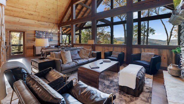 A spacious living area with a high ceiling, large windows, and a view of the outdoors.