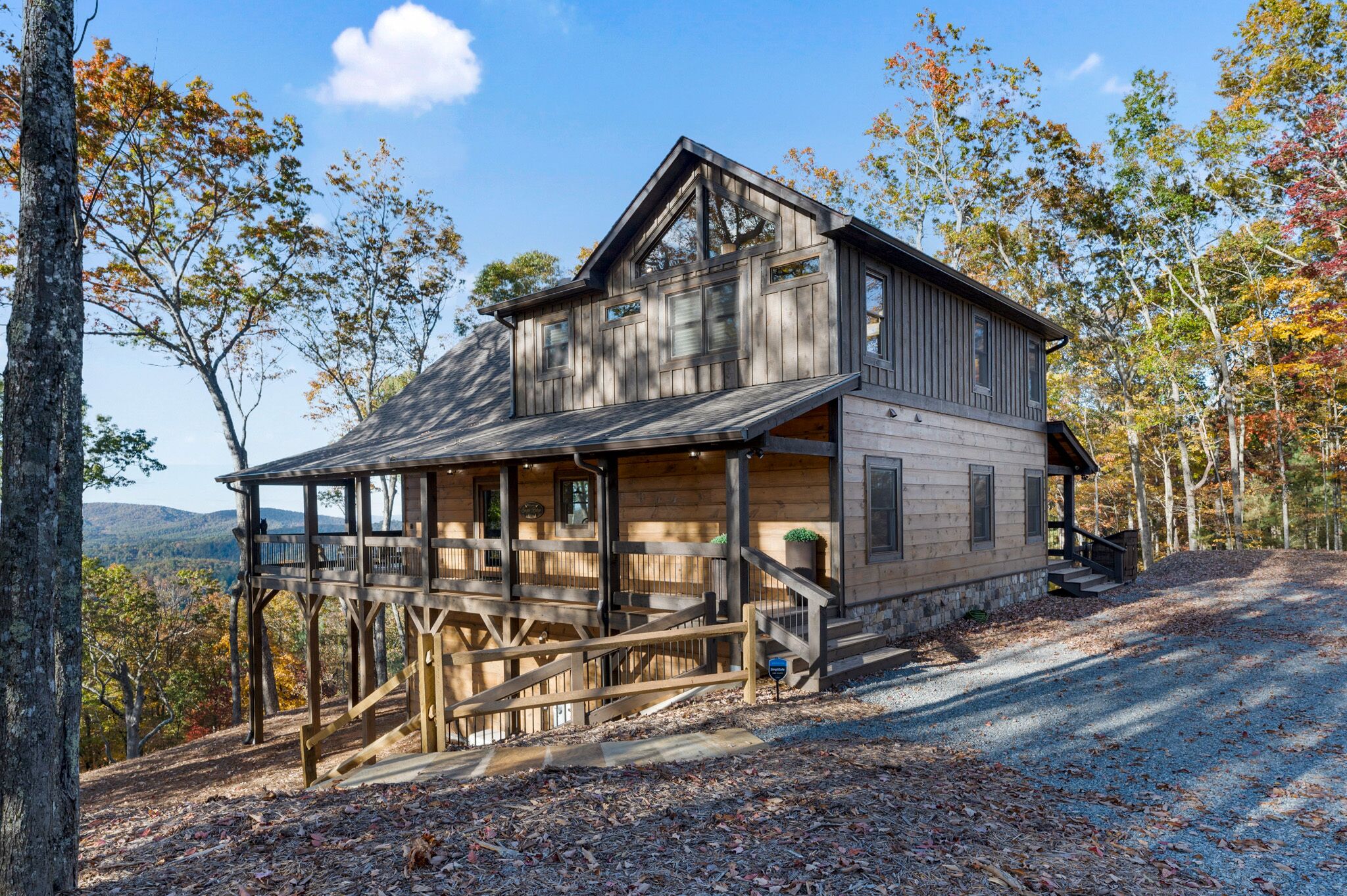 A rustic cabin with a wooden exterior, a porch, and a view of the surrounding forest.