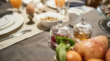 A breakfast setting with a table set for two, including plates, cutlery, glasses of orange juice, a bowl of cereal, and a bread basket.
