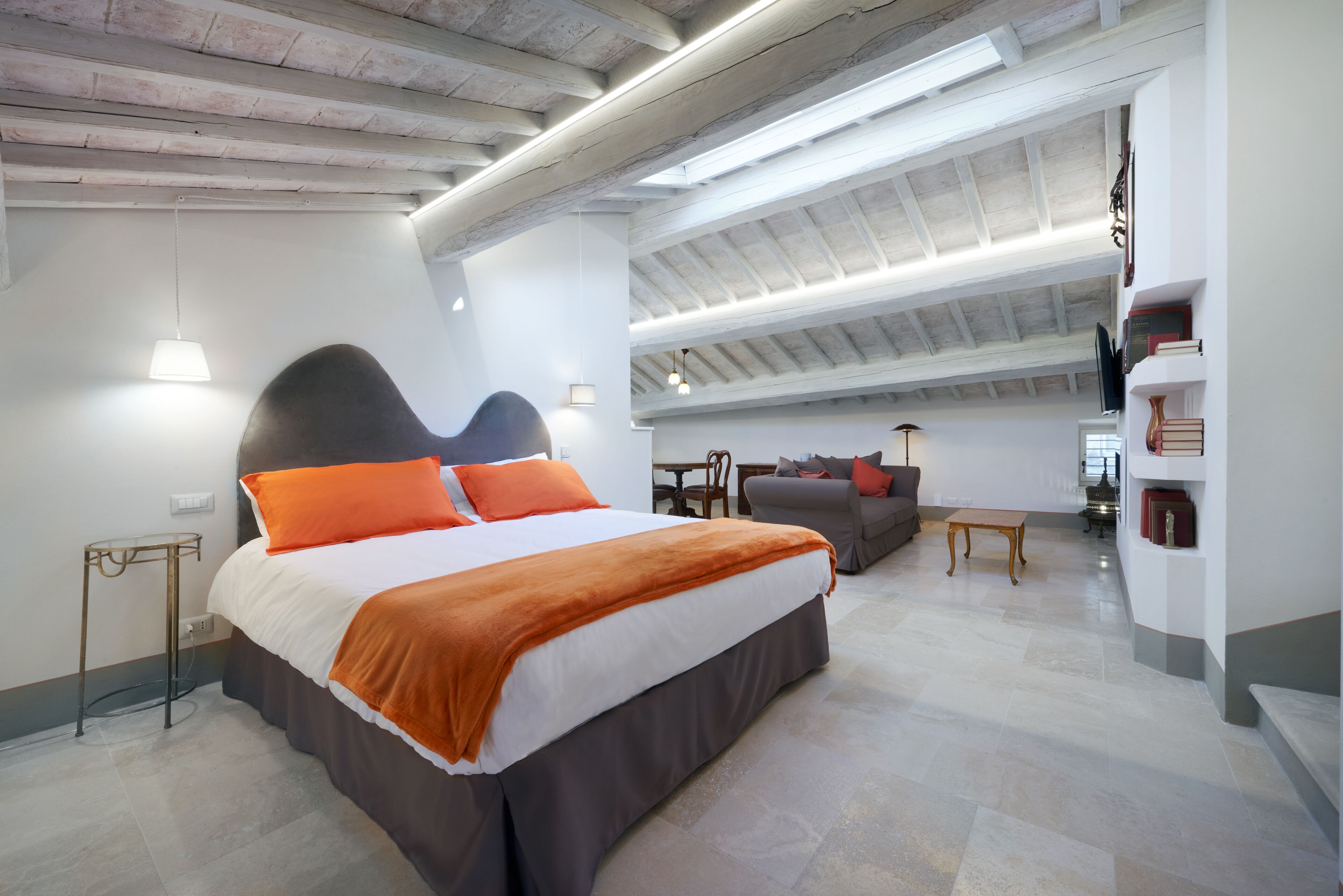 Een moderne slaapkamer met een groot bed, een bank en een zithoek.