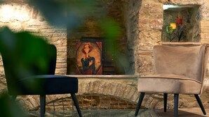 Une pièce avec une cheminée en pierre, un tableau encadré au-dessus, et un fauteuil marron placé devant.