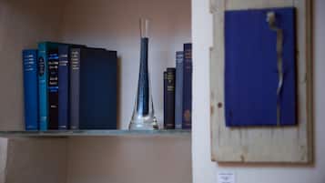 Una estantería con libros y un florero transparente.