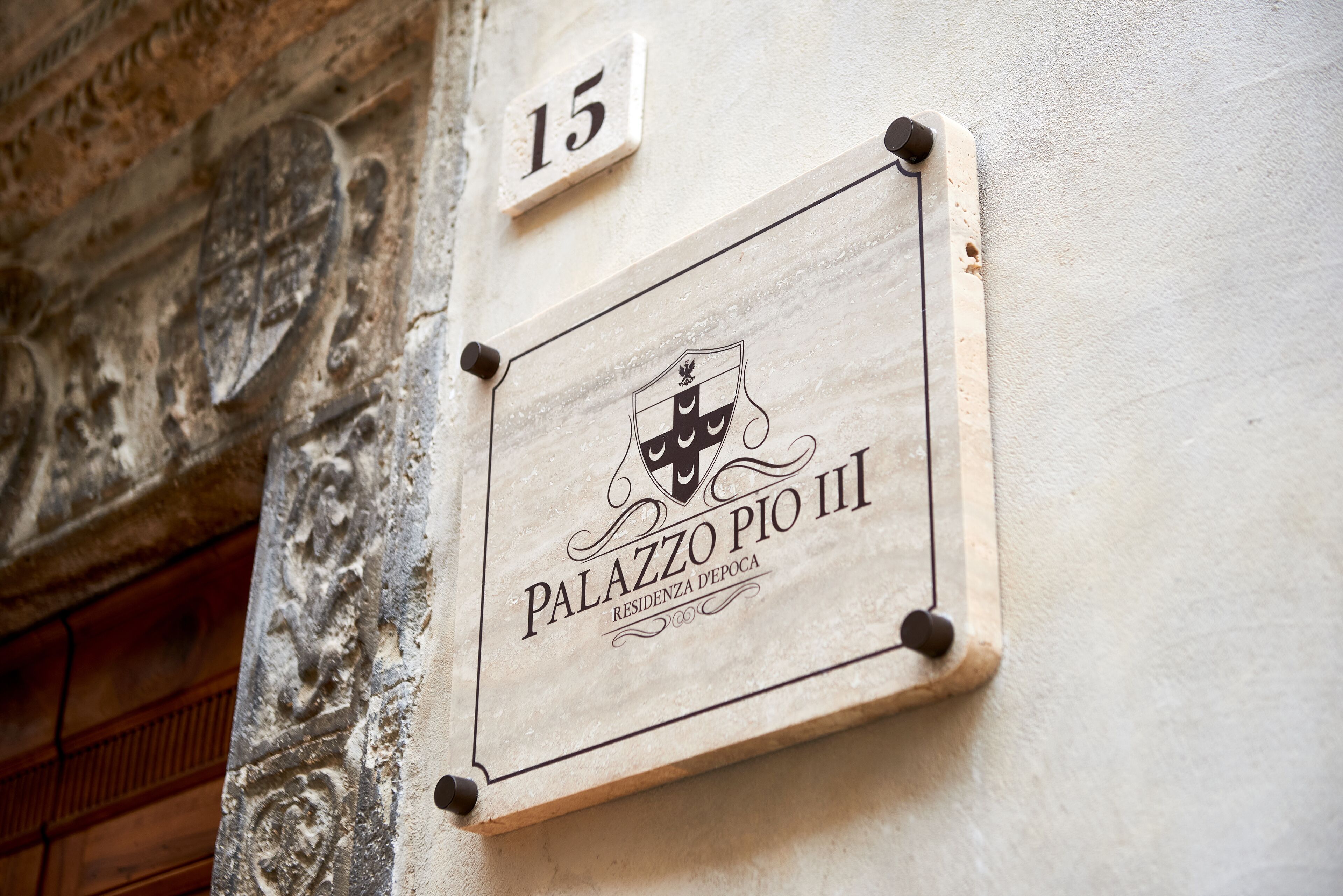 A plaque with the text "Palazzo Pio III" and "Residenza d'Epoca" on a wall, indicating a historical residence.