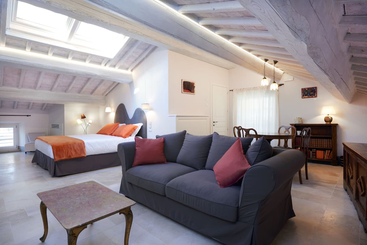 Ruime loft slaapkamer met een groot bed, een bank en een kleine tafel.