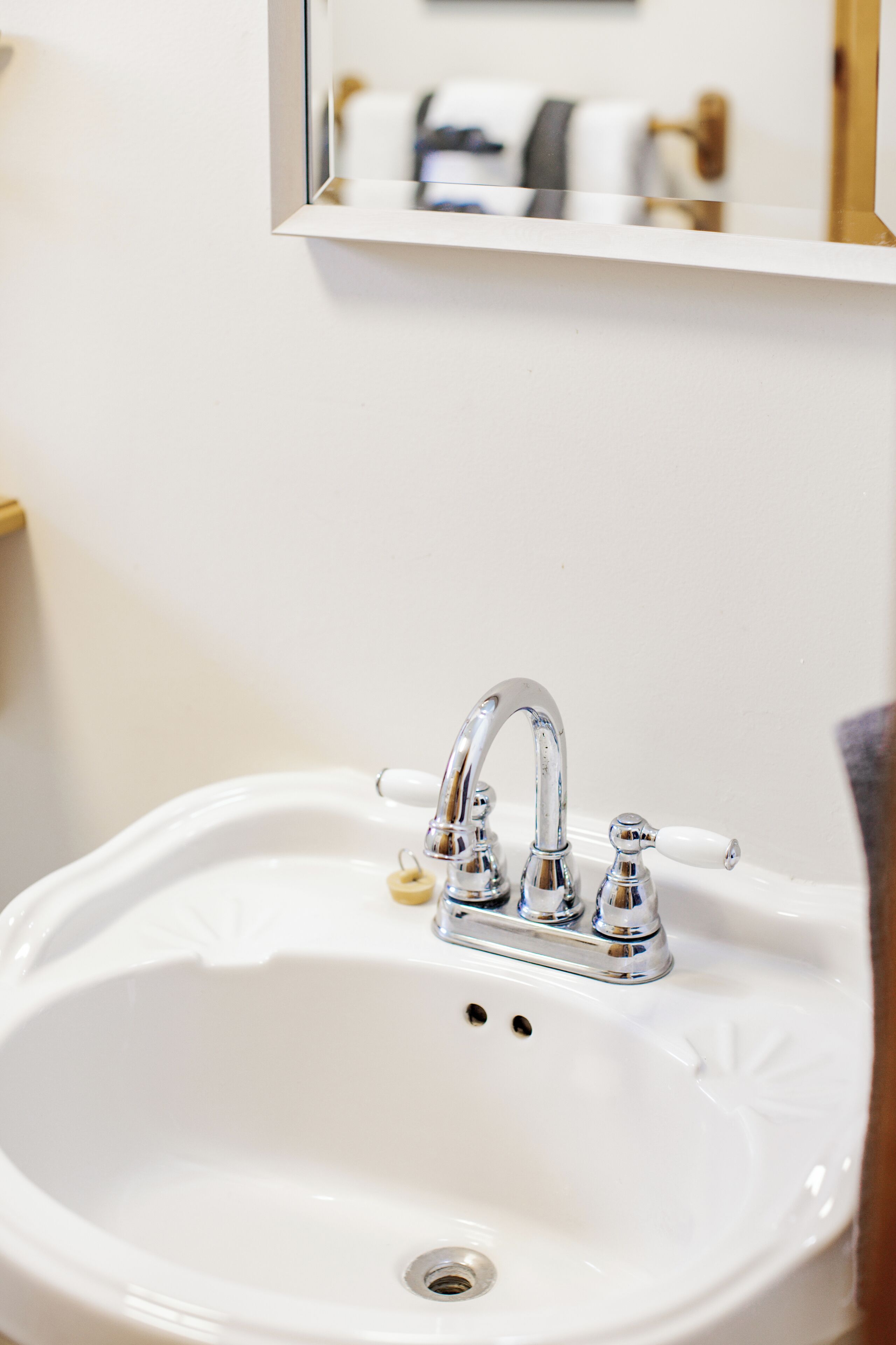 Un lavabo blanc dans une salle de bain, avec un robinet chromé et un miroir au-dessus.