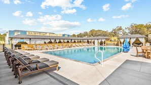 A pool area with lounge chairs and a covered seating area. - Oyster & Pearl Beautiful New Single Level Condo (Corolla)