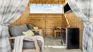 A cozy wooden cabin with a sofa, pillows, a small table, and a television. - Oyster & Pearl Beautiful New Single Level Condo (Corolla)