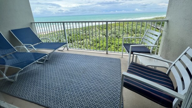 Un balcon offrant une vue sur l’océan et un paysage tropical.