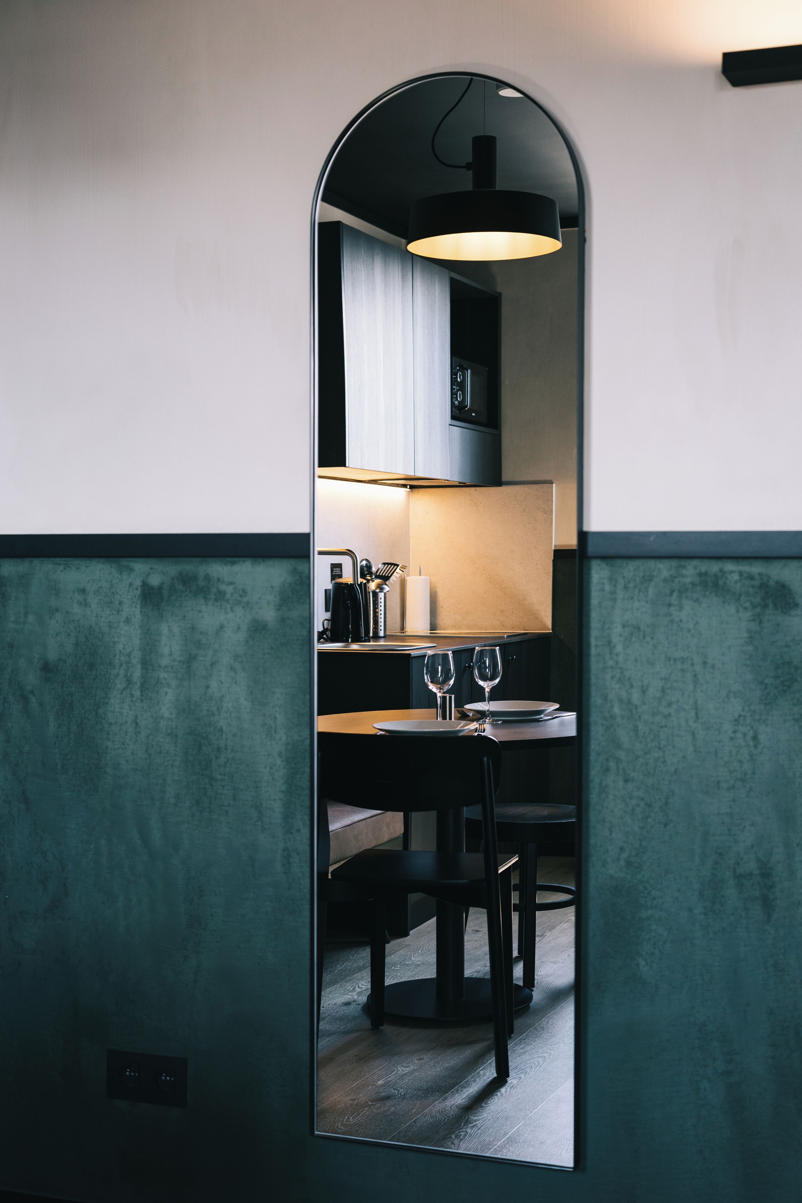 A modern kitchen with a dining area visible through a mirror.