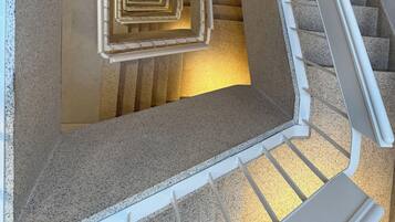Uma escadaria em espiral com corrimão e degraus carpetados.