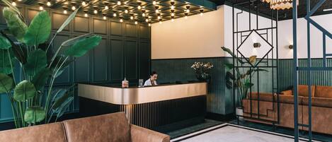 A reception area with a modern design, featuring a reception desk, a brown sofa, and a chandelier.