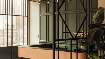 A modern reception area with a geometric light fixture, a reception desk, and a large window offering a view of the city.