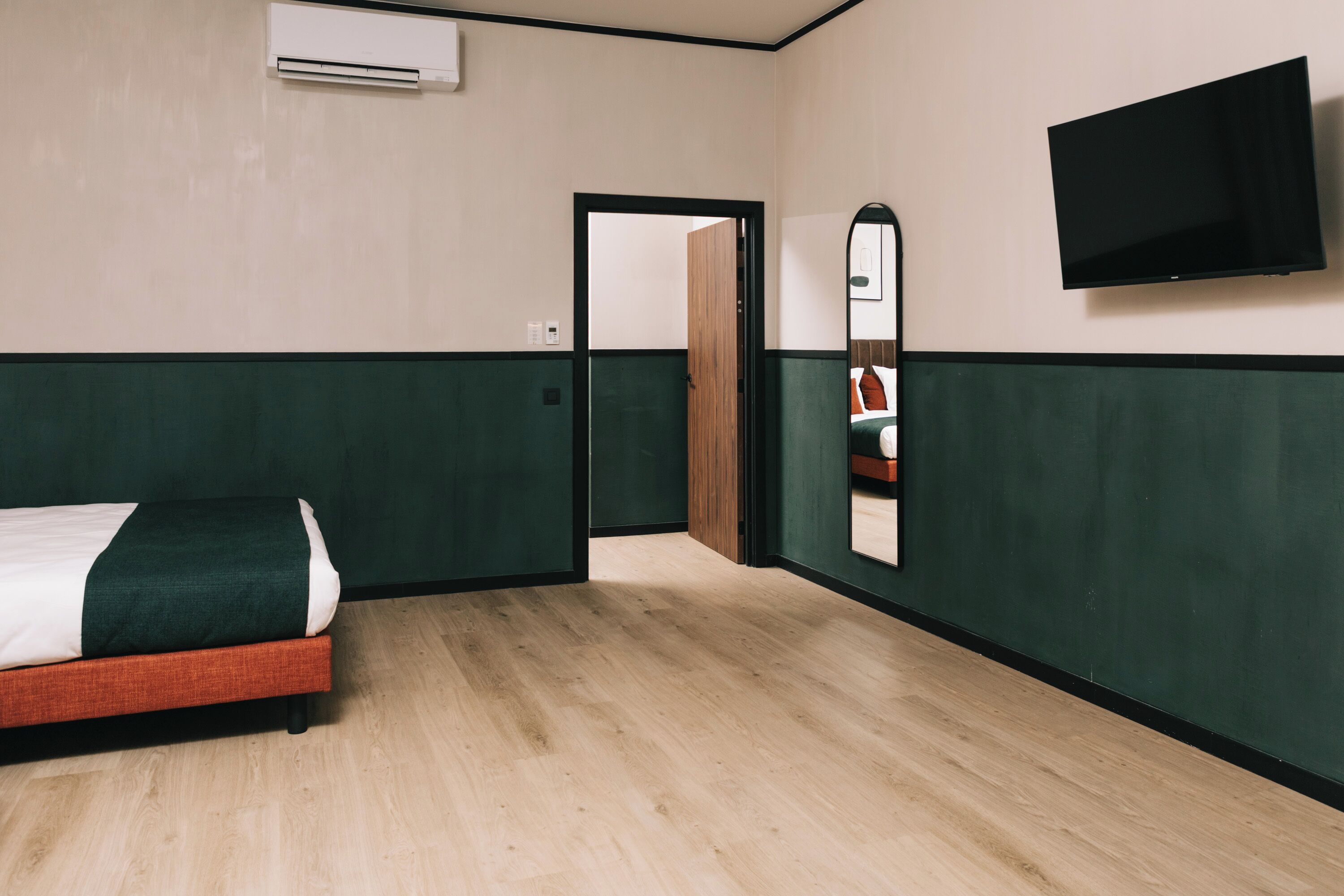Une chambre d’hôtel équipée d’un lit, d’un téléviseur à écran plat fixé au mur et d’un appareil de climatisation.