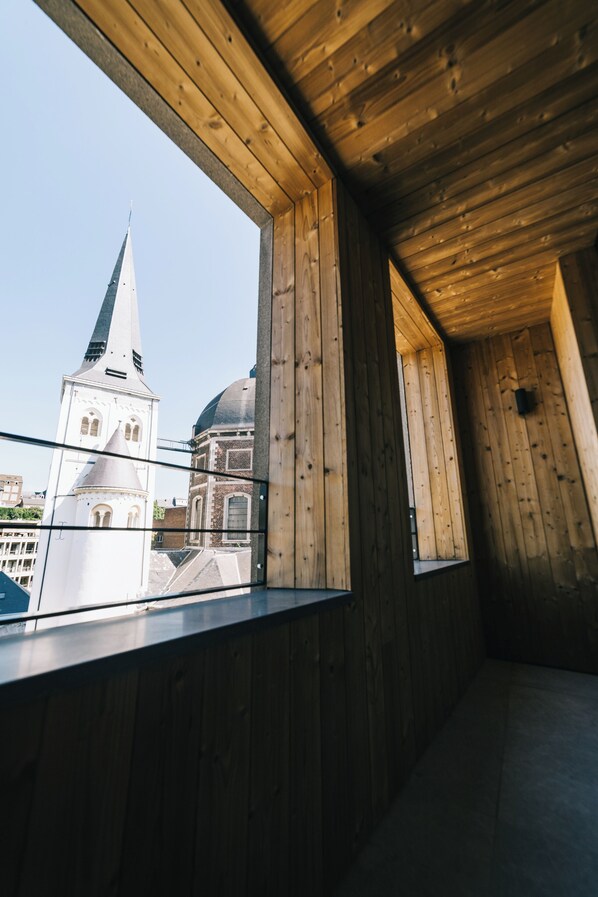A room with wooden walls and a large window offering a view of a church with a tall spire and a dome. - Getaway Liège (Liege)
