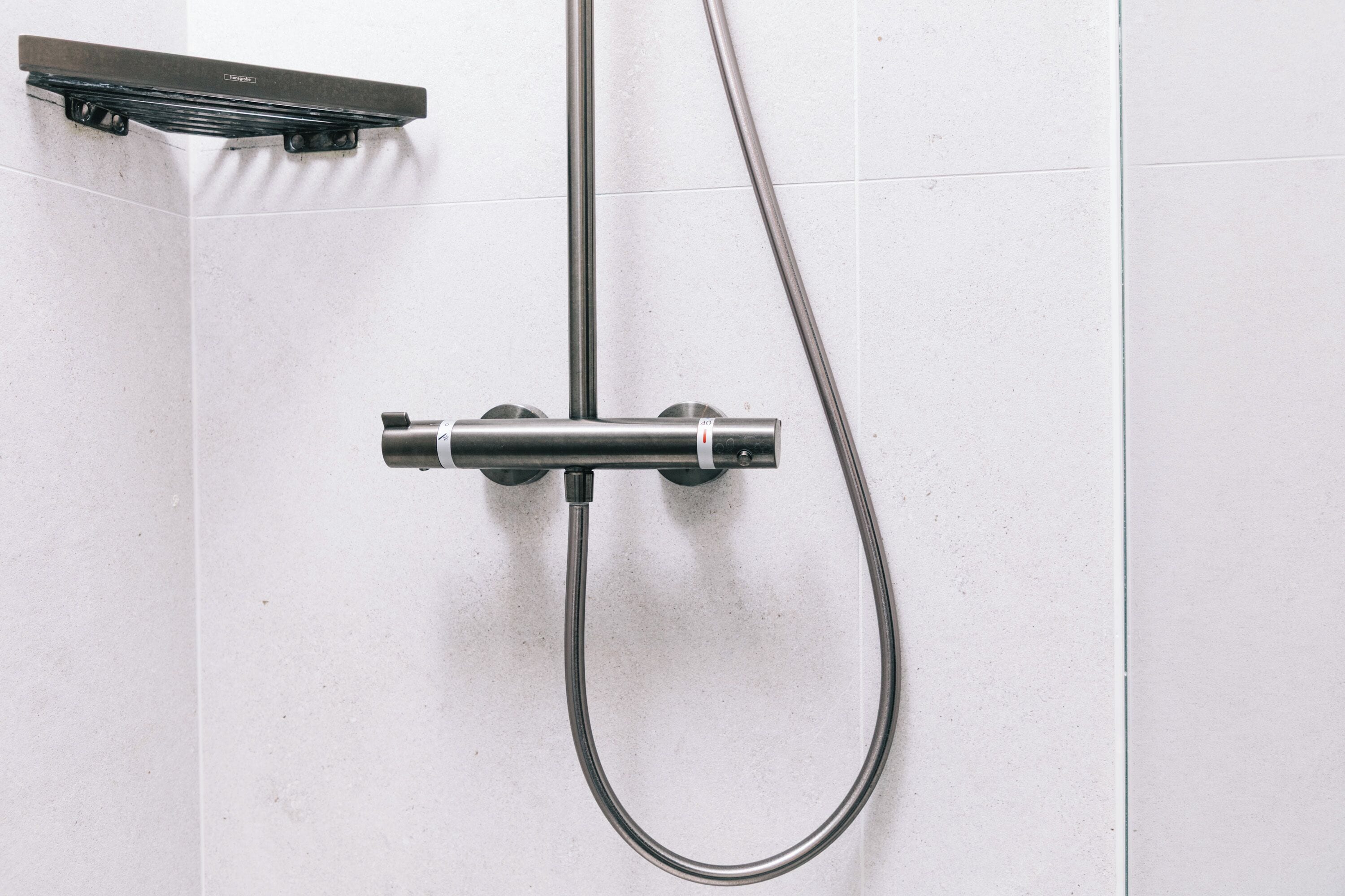 Une douche équipée d’un pommeau de douche à main et d’un pommeau de douche fixe fixé au mur.
