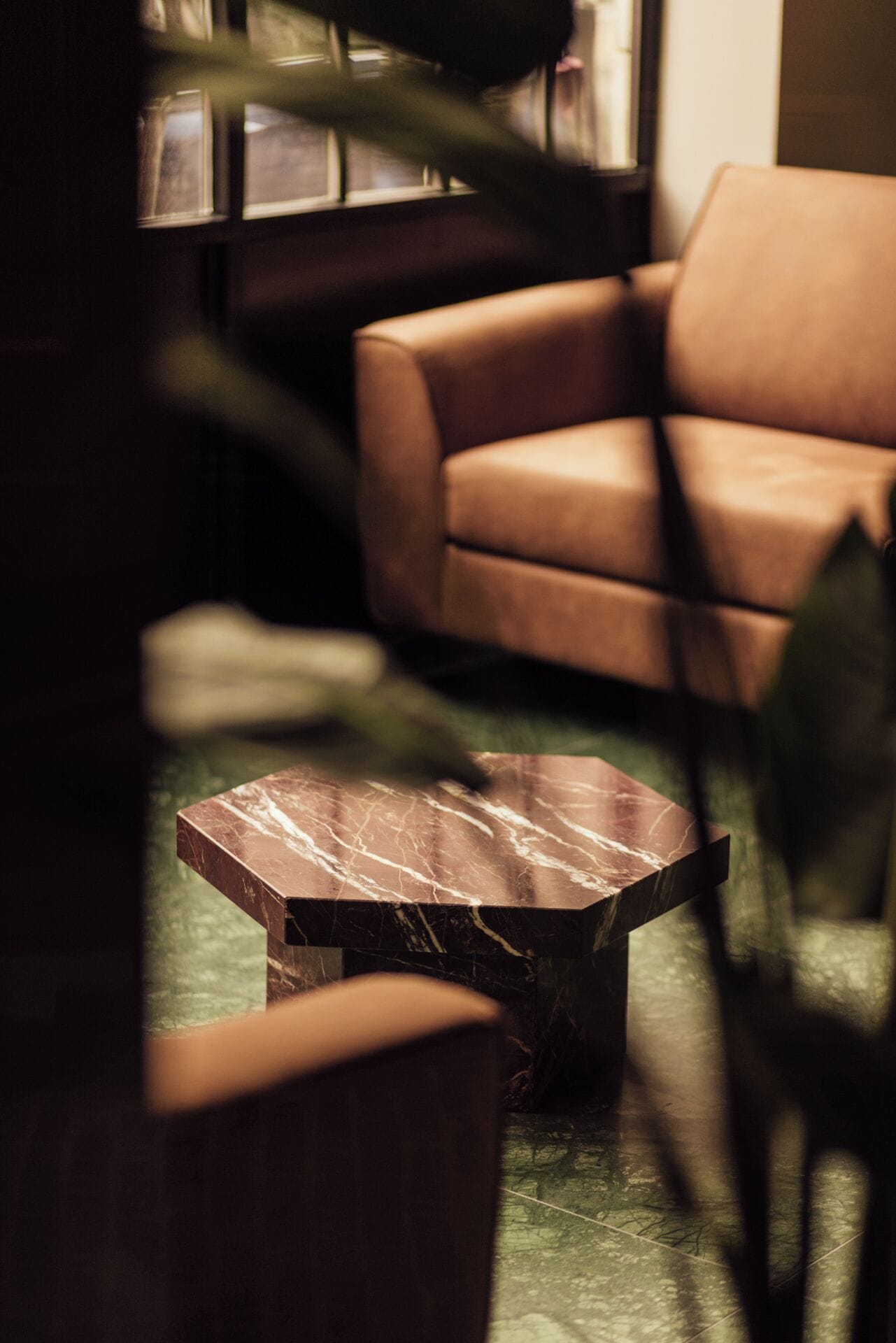 A modern living room with a leather sofa, a marble coffee table, and a wooden side table.