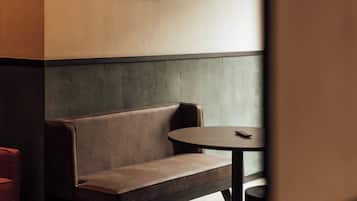 Een modern interieur met een bankje en een tafel, een hanglamp en een lijst met abstracte kunst aan de muur.