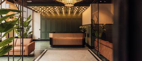 A modern lobby with a central seating area, a patterned ceiling, and green walls.