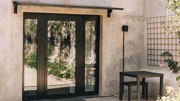 Ein modernes Interieur mit einer Schiebeglasdoor zu einem Garten, einem kleinen Tisch und einer Wandleuchte.