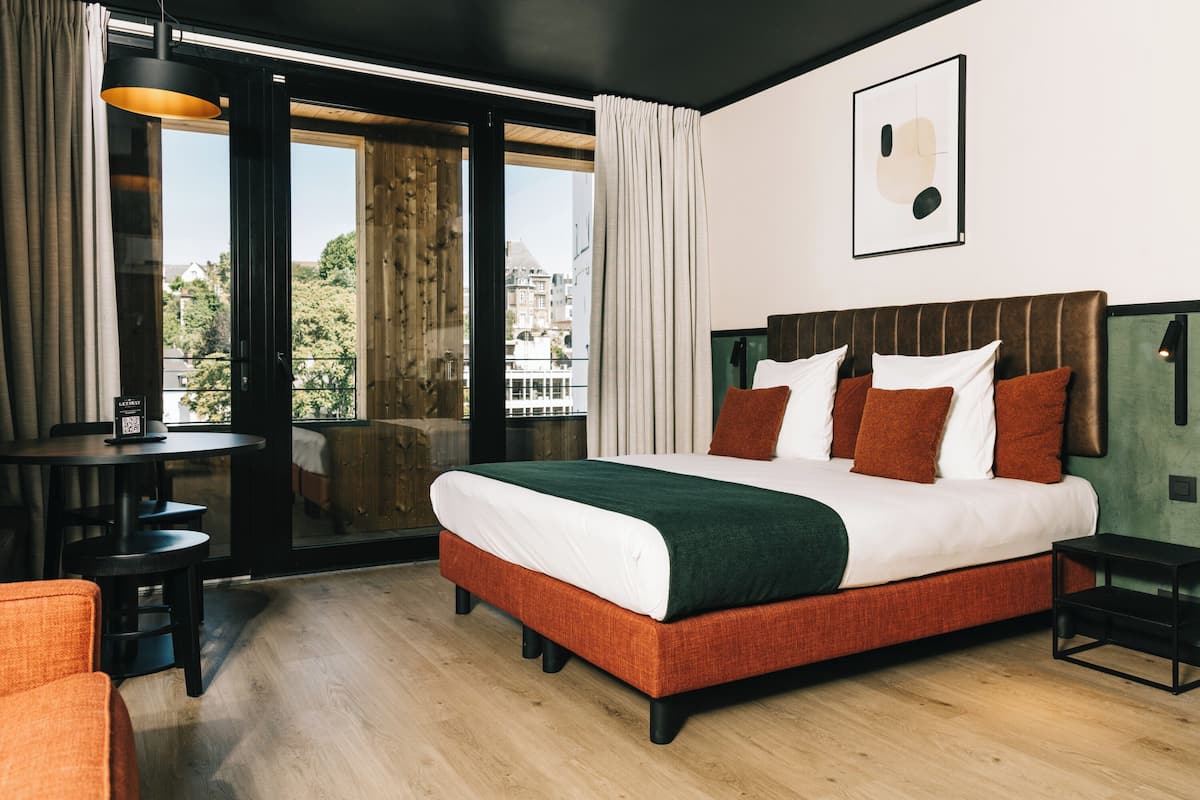 Ein modernes Hotelzimmer mit einem großen Bett, einem Schreibtisch und Blick auf die Stadt.