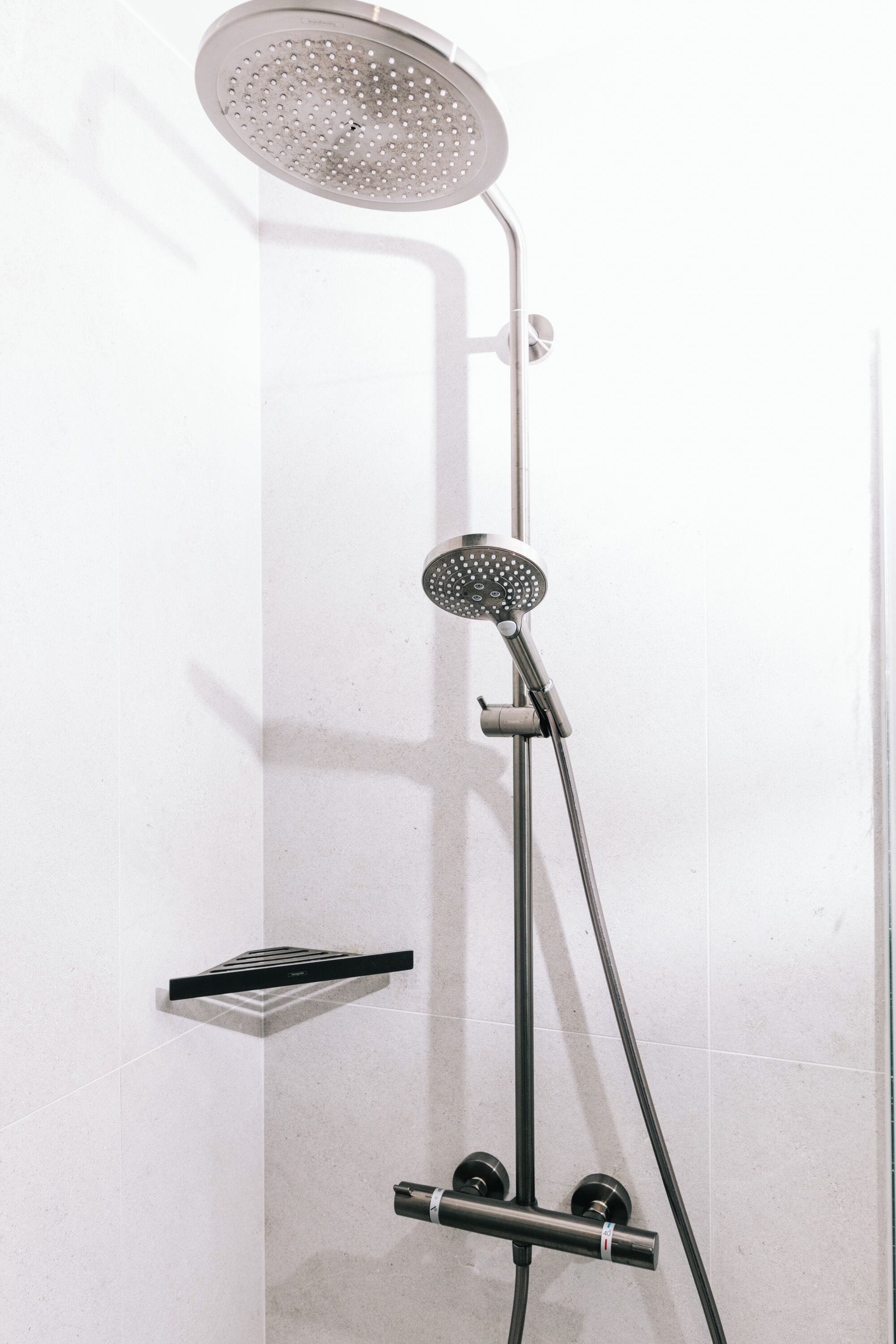 A modern shower with a handheld showerhead and a fixed overhead rain showerhead.