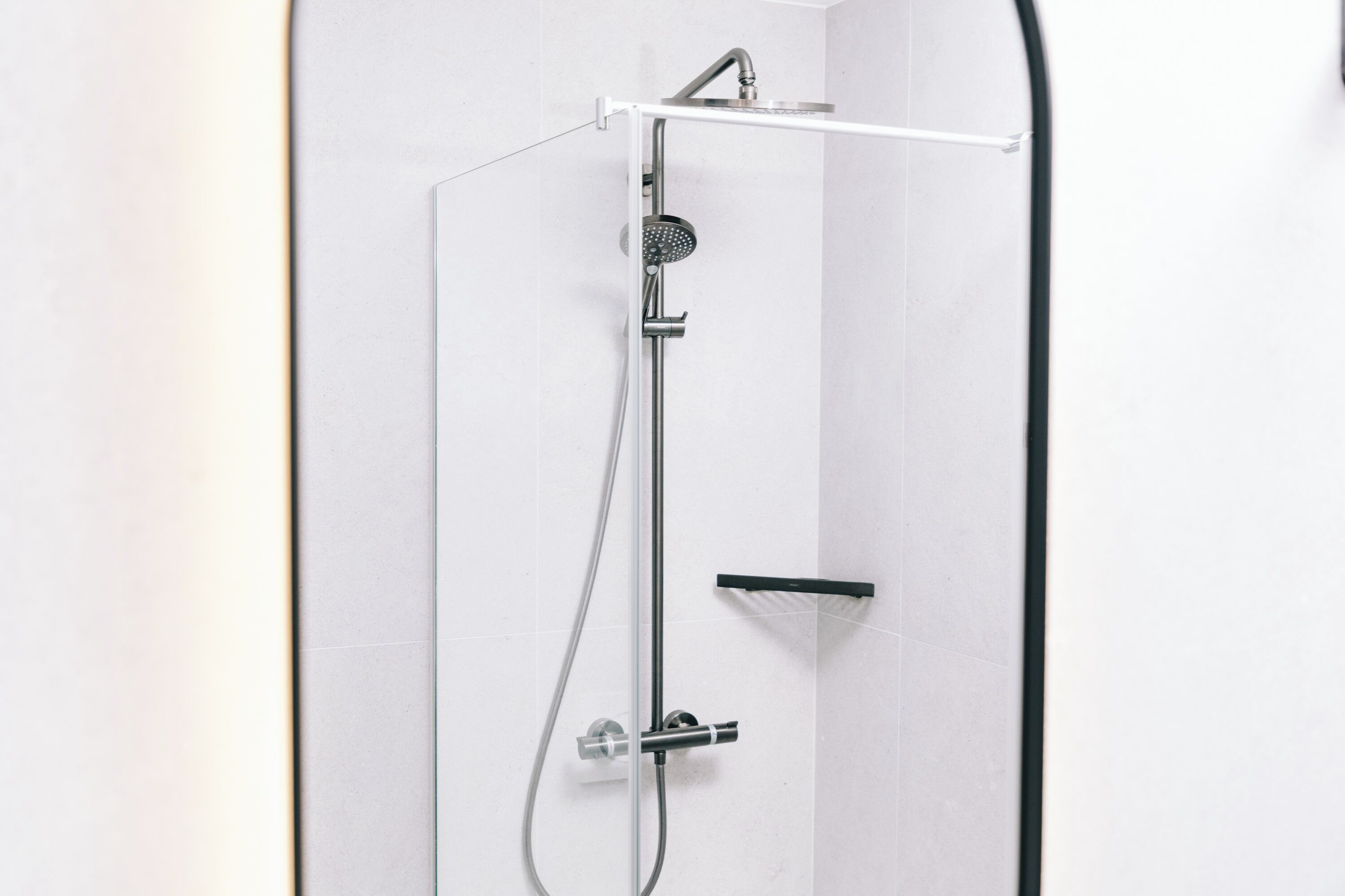 A modern shower with a handheld showerhead and a wall-mounted control panel.