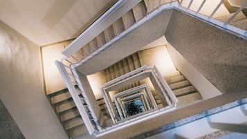 Un escalier en colimaçon avec des rampes blanches et un revêtement de sol en moquette.