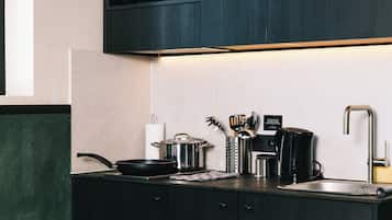 A modern kitchen with dark cabinetry, a stainless steel sink, a coffee maker, and a microwave.