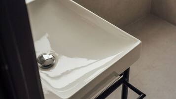 Une petite salle de bain avec un lavabo blanc, une serviette suspendue à un porte-serviettes et une fenêtre au-dessus du lavabo.