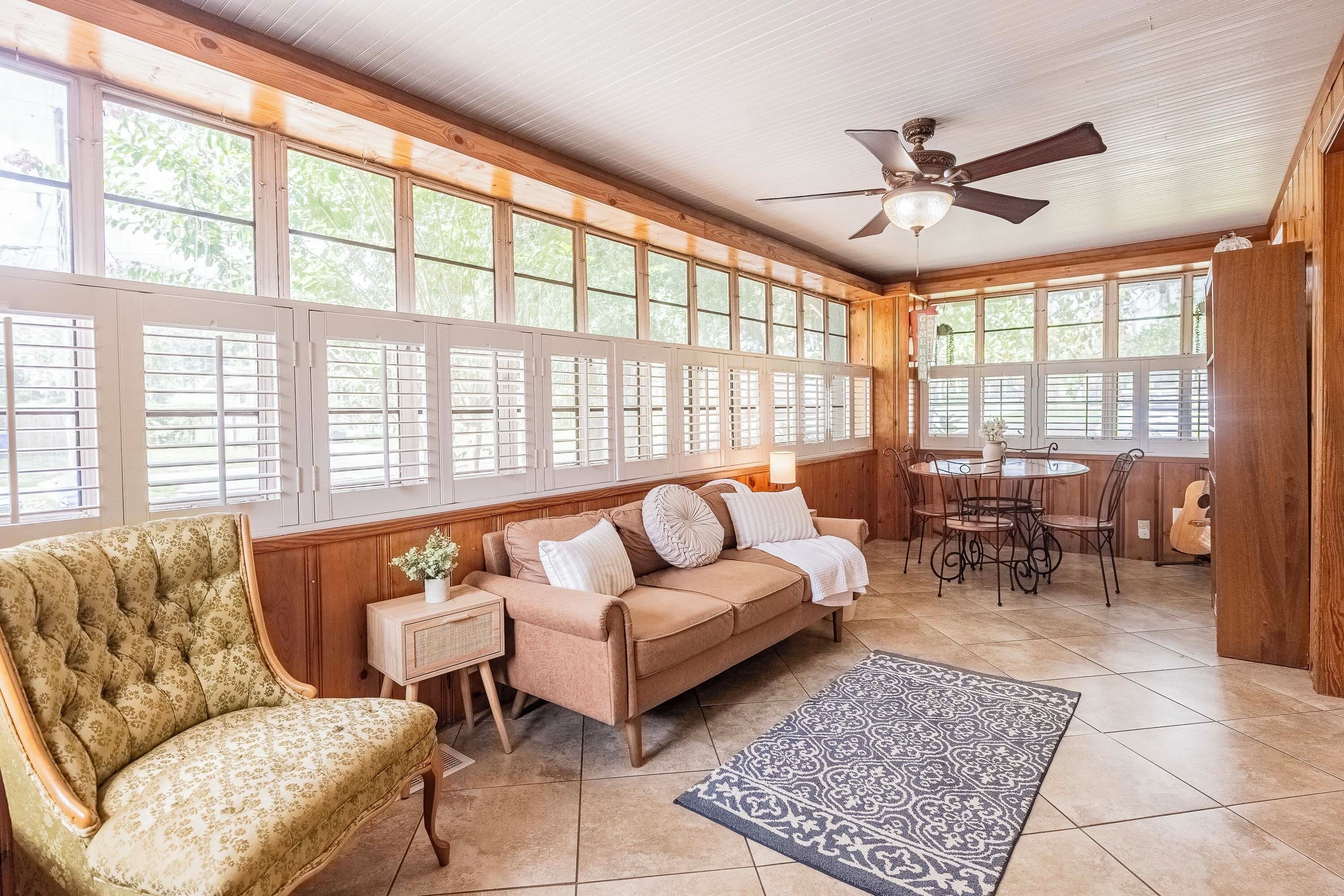 A cozy room with a sofa, armchair, and a dining area with a table and chairs.