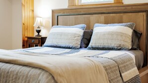 Una cama con cabecera de madera, dos almohadas y colcha.