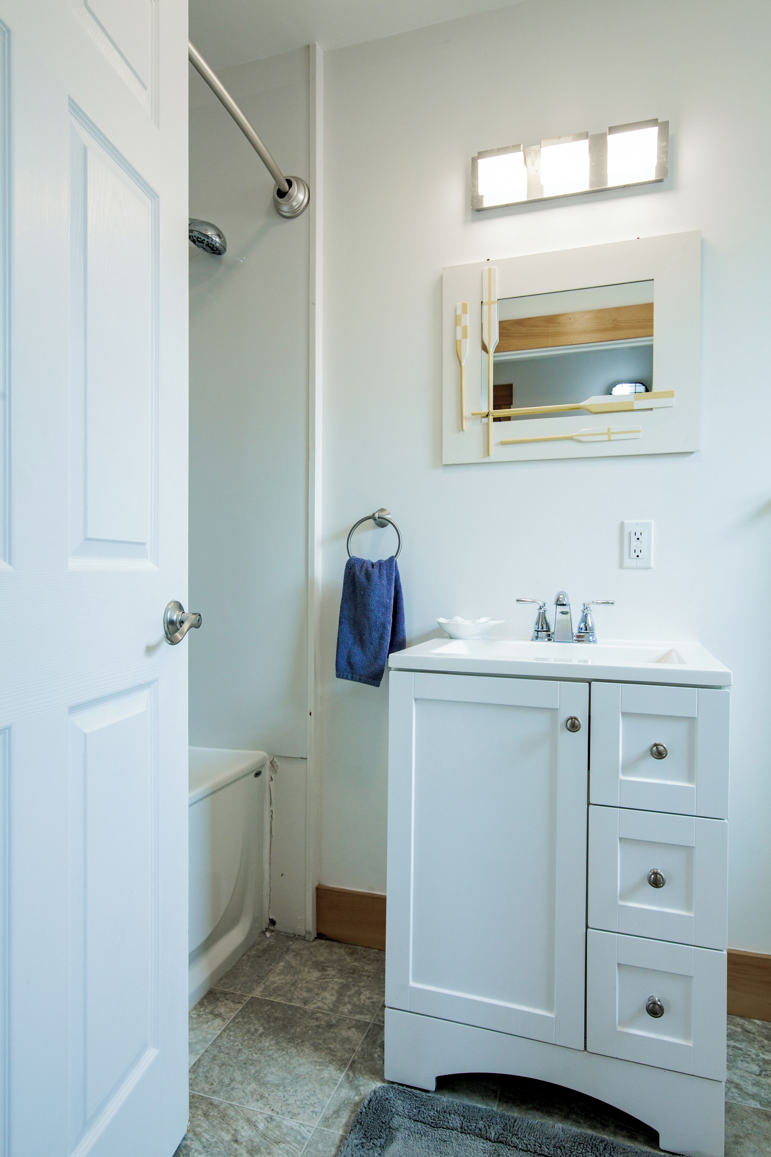 A bathroom with a white sink, mirror, and towel rack.
