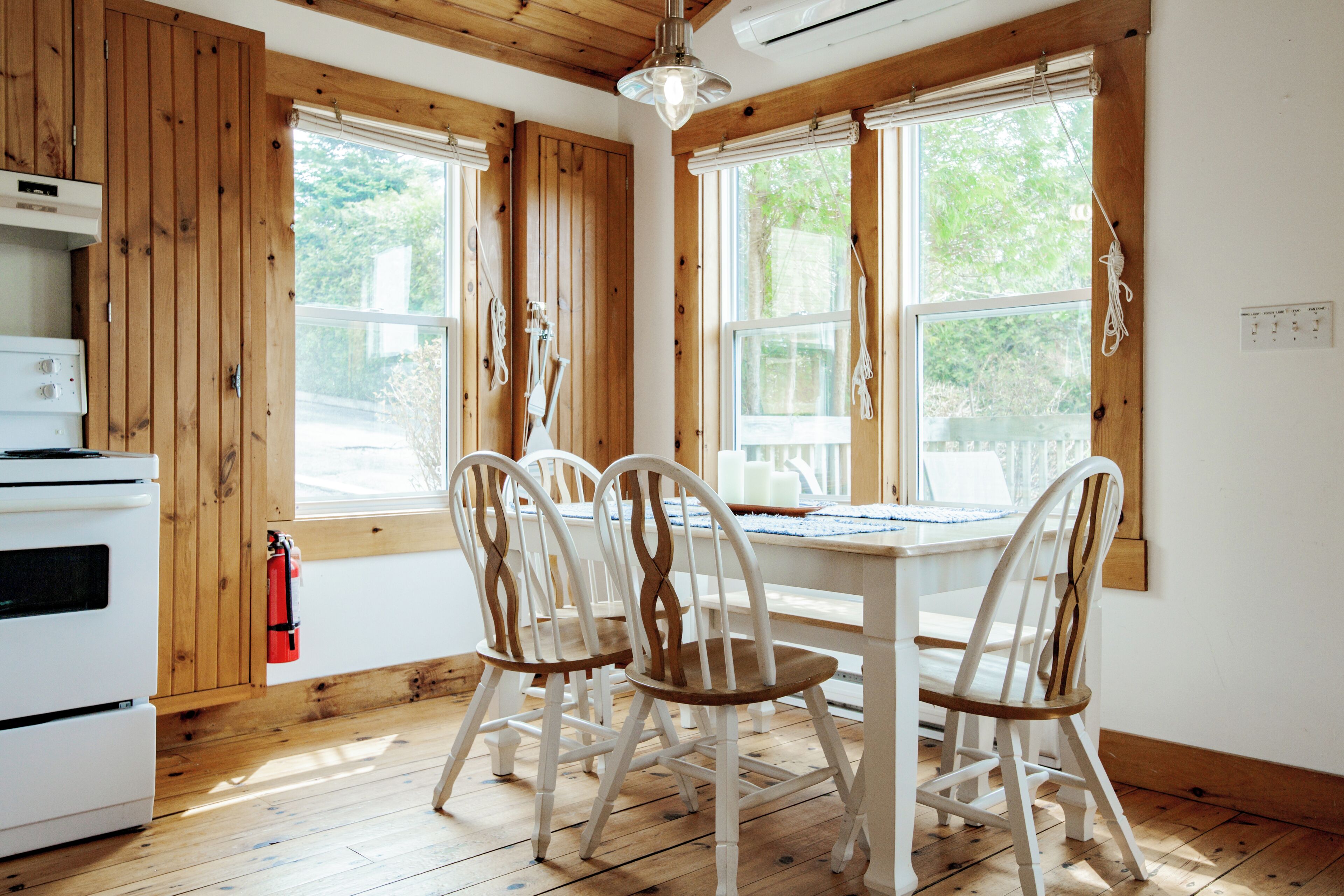 A kitchen with wooden walls, a white stove, and a dining table with four chairs.