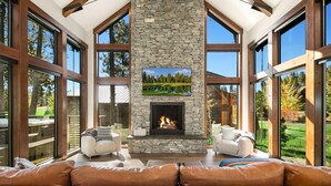 A spacious living room with a stone fireplace, large windows, and leather sofas. - Suncadia's #1 6BR/6BA Luxury Retreat! Huge Swim Spa*Hot Tub*Game Room*5 Mstrs (Cle Elum)