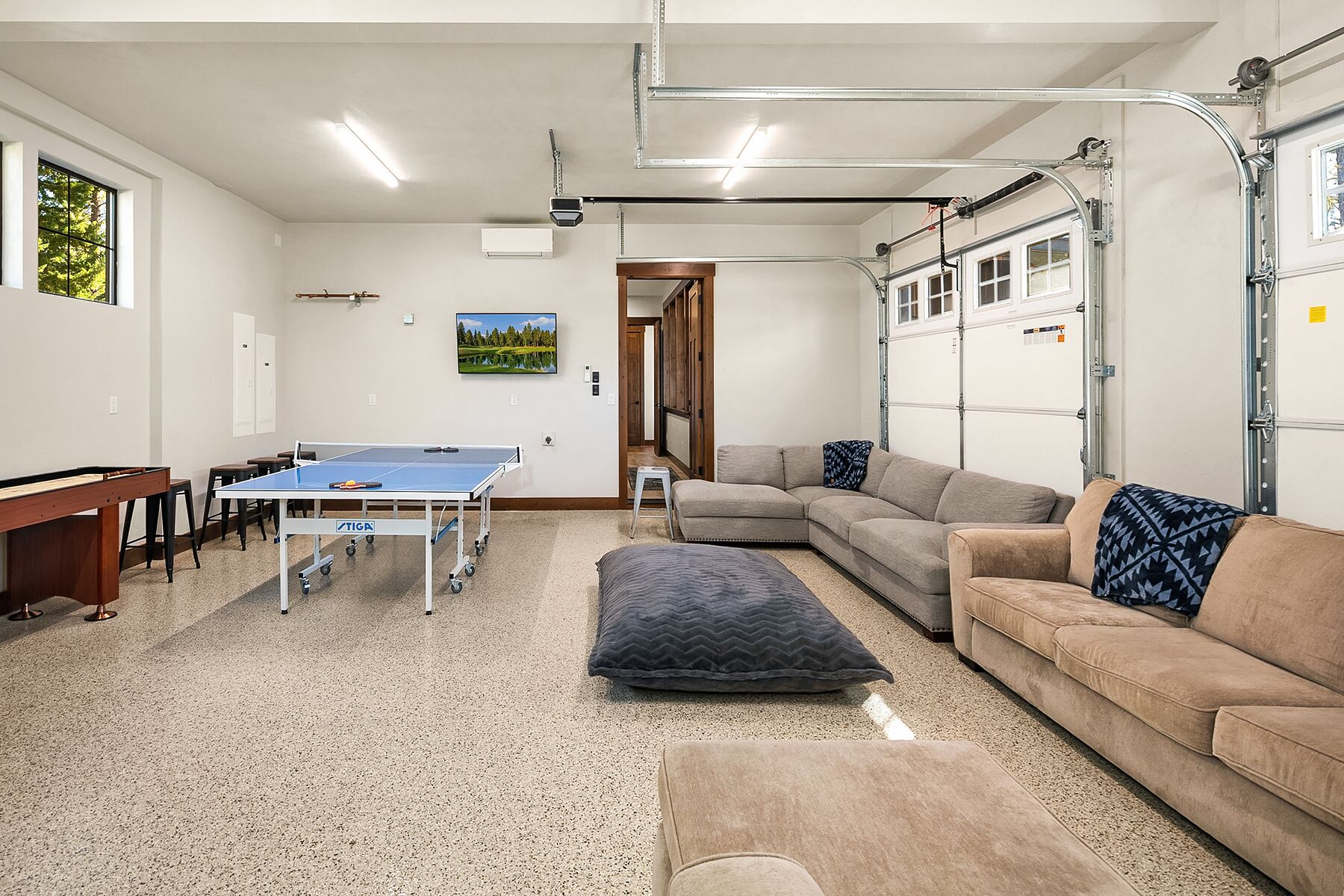 A spacious living area with a ping pong table, a sofa, and a couch.