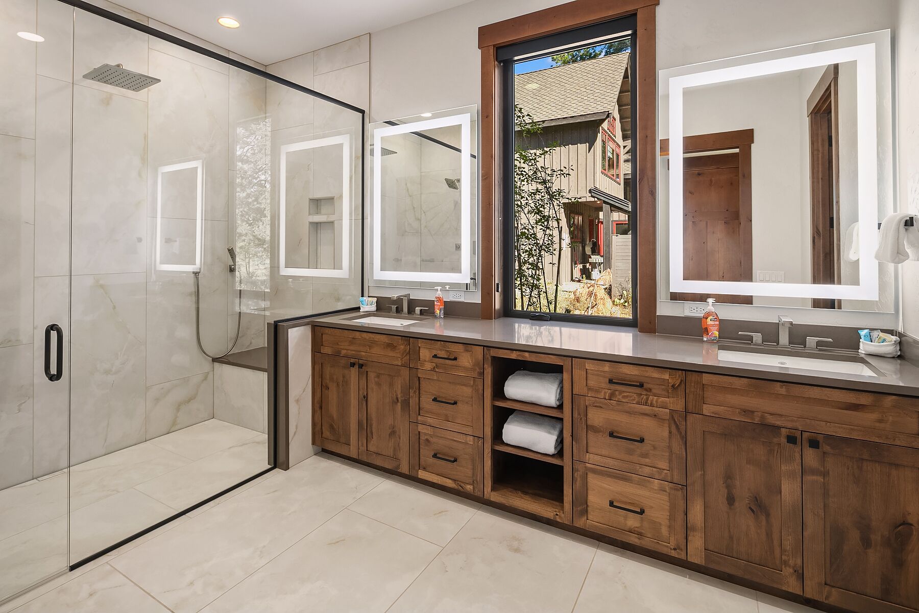 Ein modernes Badezimmer mit Duschkabine aus Glas, einem Holzbadezimmer-Möbelstück und Blick ins Freie.