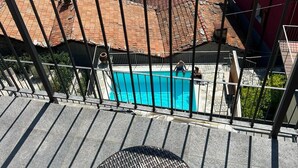 A balcony with a view of a swimming pool, terracotta-roofed buildings, and a distant church spire. - Amazing Lage View Apartment With Pool and 2 Terraces (Calozzo)