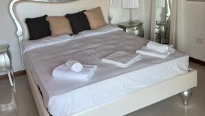 A neatly made bed with white linens and rolled towels, a bedside lamp, and a mirror on a nightstand. - Amazing Lage View Apartment With Pool and 2 Terraces (Calozzo)